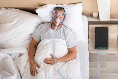 young adult man sleeping with cpap machine and mask