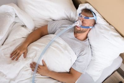 adult man sleeping in bed with cpap mask on