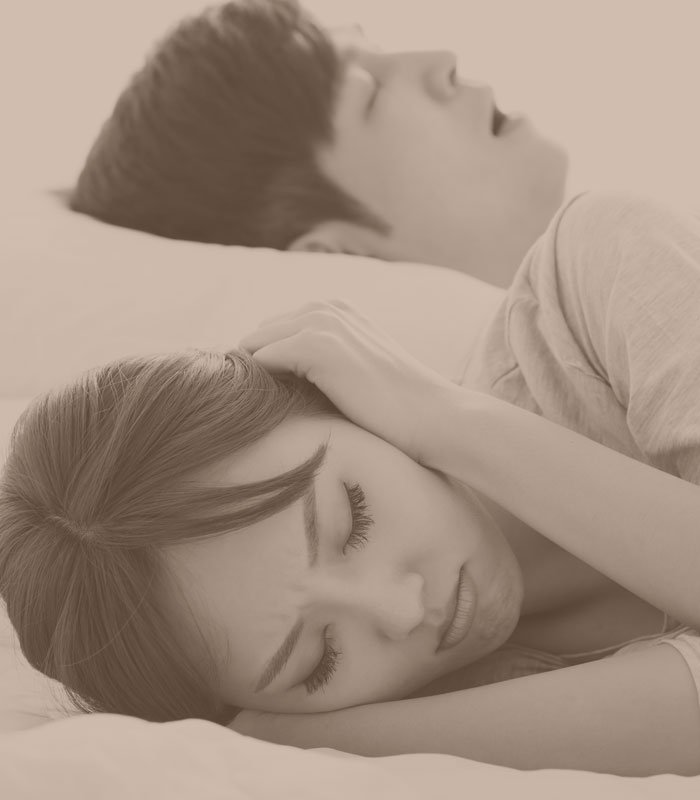 woman laying next to her snoring husband